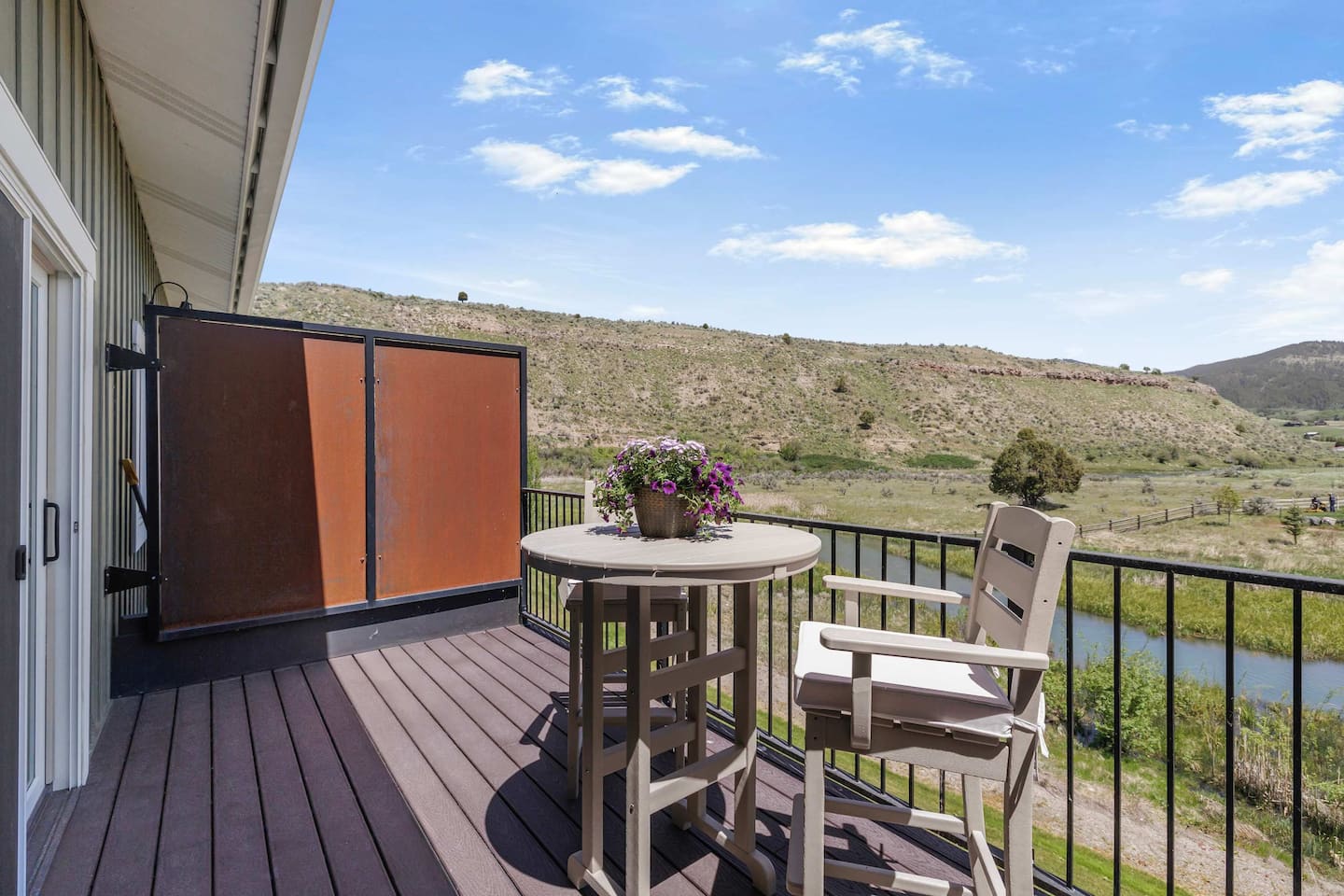 Creekside patio with outdoor seating and a grill overlooking Rainey Creek